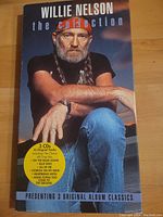 Front cover showing Willie Nelson sitting wearing a red bandana, black shirt, and blue jeans with yellow sticker listing key songs included.
