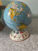 Front view of vintage metal globe showing map of Americas and base with airline logos