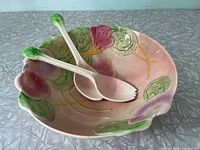 Top view of floral ceramic salad bowl with matching salad tongs inside, showing colorful hand-painted flowers and slight discoloration.