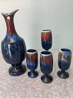 Photo showing the carafe and four matching glasses with multicolor glossy glaze in blue, red, and cream.