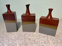 Three ceramic vases with tri-colour glaze, square-shaped bases, and narrow necks.