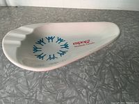 White plastic ashtray featuring Expo 67 Montreal Canada text and blue logos, photographed on textured gray surface.