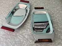 Two Glo-Hill polished metal serving trays lying flat, showing their rectangular shape and Bakelite handles with one tray featuring red handles and the other a tortoiseshell pattern.