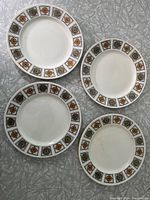 Four Kathie Winkle designed ironstone plates with Broadhurst Michelle pattern arranged on textured grey surface.