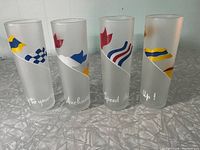 Front view of four frosted vintage highball glasses with colorful nautical signal flags and white script text