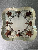 Square Limoges tray with scalloped edges displaying floral design on iridescent cream background.
