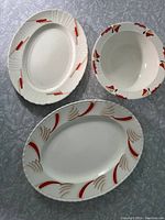 View of two oval platters and one round bowl showing hand painted red and beige designs and crazing on platters.
