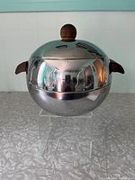 Front view of the stainless steel vintage server showing polished finish and wood handles with penguin embossing on body.