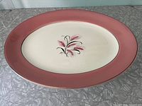 Full view of the oval platter showing the pink rim and decorative wheat motif in the center.