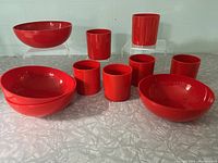 Photo of six red plastic Dansk cups and four red plastic Design Motivation Ltd. bowls against a neutral background