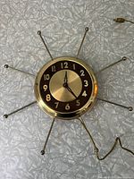 Full view of the electric starburst wall clock showing starburst rays and clock face with original cord visible.