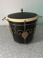 Black insulated Thermos ice bucket with lid inside gold-tone decorative metal holder with leaf and scrollwork design.