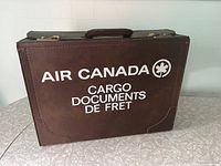 Front view of the brown leather Air Canada cargo documents case with white printed text and maple leaf logo.