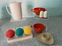 Display of all vintage kitchenware items including pitcher, creamers, salt and pepper shakers, egg cup, and spice rack.