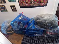 Six large bags filled with men's clothing placed on the floor, bags are tied and packed.