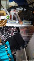 Photo of crafting materials piled including storage boxes, fabric, and yarn supplies.