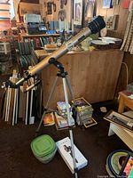 Full view of the Bushnell telescope on aluminum tripod stand with accessories nearby, showing length and height.