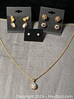 Image showing aquamarine pendant necklace on gold chain along with four pairs of earrings displayed on black and gray backgrounds.