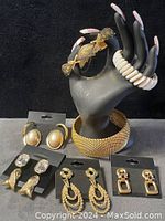 Lot displayed on black and gray background showing all pieces: earrings on display card and bracelets on black hand model.