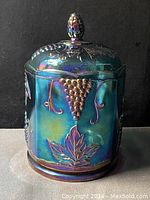 Front view of the Indiana Harvest Grape carnival glass canister with lid showing grape clusters and leaves pattern.