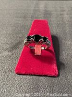 Front view of the ring showing three black stones and smaller clear stones on the band.