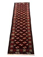 Full view of the Persian Turkmen runner rug showing overall length and intricate geometric patterns in dark red tones.