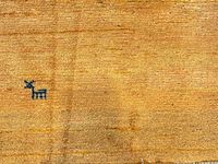 Close-up photo showing the yellow wool texture and a small blue goat motif woven into the fabric.