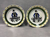 Two collectible plates side by side showing identical design of a stylized man sitting on a bench, with a geometric border in yellow, green, and blue.