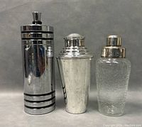 Front view of three Mid-Century Modern cocktail shakers showing different styles and sizes.