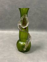 Green glass Art Nouveau style vase with applied clear glass flower decoration shown from front angle.