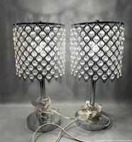 Pair of crystal table lamps with chrome bases and crystal bead lattice shades, cords coiled at bases