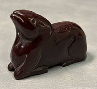 Front angled view of the polished reddish-brown stone ram figurine on a neutral background.