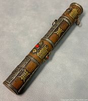 Angled view of the copper scroll case showing metal inlaid characters and red stone accents