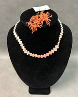 Natural coral earrings and necklace displayed on black bust and grey surface showing details and condition.