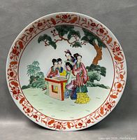 Front view of the 16-inch oriental hand-painted porcelain platter featuring four women around a table with trees in the background and orange floral border