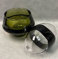 Angle showing the green glass bowl with black tinted rim alongside the clear and black art glass egg.