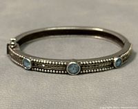 Front angle showing the three round blue gemstones and detailed beadwork on the sterling silver bangle bracelet.