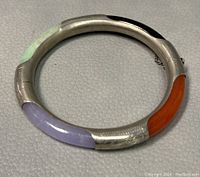 Photo showing top view of vintage sterling silver bangle with four multi-color jade inlays and safety chain.