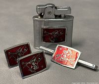 Close-up of lighter, cufflinks, and tie clip showing red enamel polo player motif on silver-tone metal.