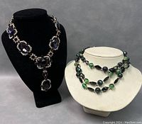 Photo shows two necklaces displayed on necklace stands, highlighting their design and condition.