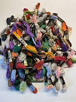 Overhead photo of a large pile of multicolored embroidery yarn skeins showing the range of colors and the label style.