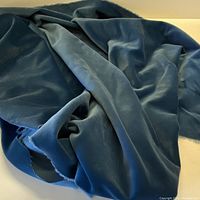Photo showing soft, draped blue-grey velvet fabric with visible texture and nap.