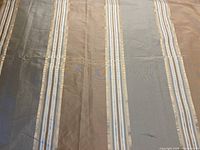 Full view of the striped silk fabric held out to show width and color variation in earthy muted tones