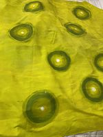 Full view of the fabric showing lemon and lime background with green spheres hand painted in various positions.