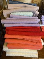 Stacked 23 pieces of wool fabric in various colors including pastel purples, reds, oranges, creams, and white.