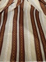 Close-up of woven fabric showing cream background with coffee brown, white, and tangerine vertical stripes with looped surface thread details.