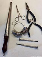 Full view of all jewellery maker tools including mandrel, ring sizer, pliers, clamp scissors, two small screwdrivers
