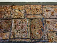 Close-up photo showing patchwork metallic thread embroidered fabric in geometric shapes on cotton backing