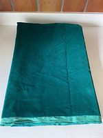Folded piece of deep green rayon velvet fabric showing full yardage width and length folded neatly.