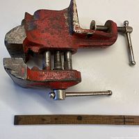 Side view of the red vice grip showing the adjustable screw handle and clamp mechanism, next to a measuring stick indicating about 8 inches width.